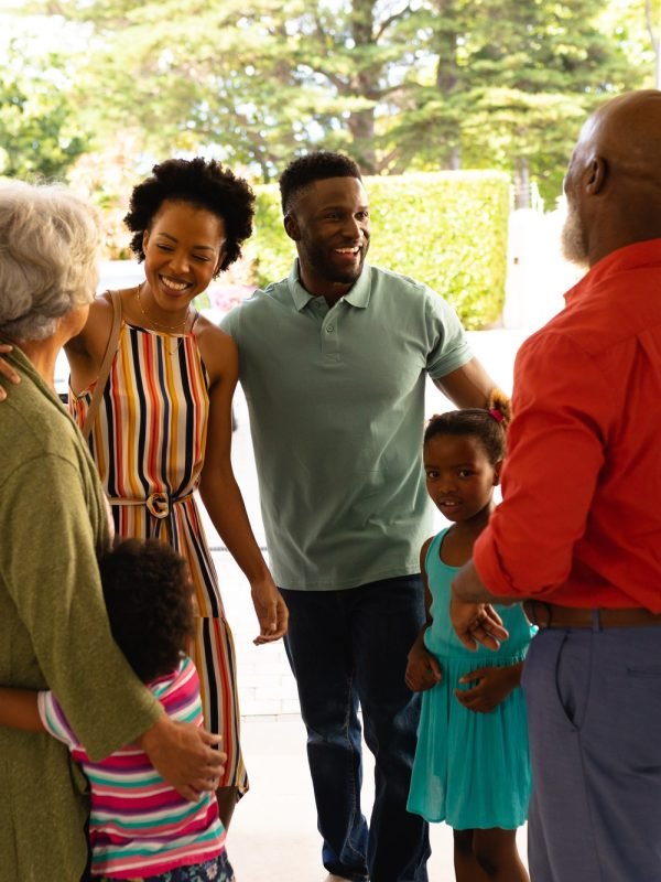 African american senior couple welcoming their family while standing on the front door at home