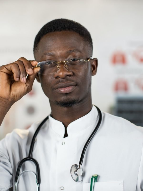 Black health care worker adjusting his eyglasses at cabinet