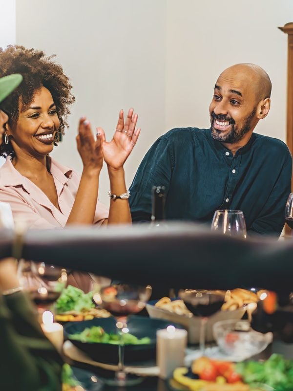 Diverse Friends Sharing Laughter and Food at Dinner Table