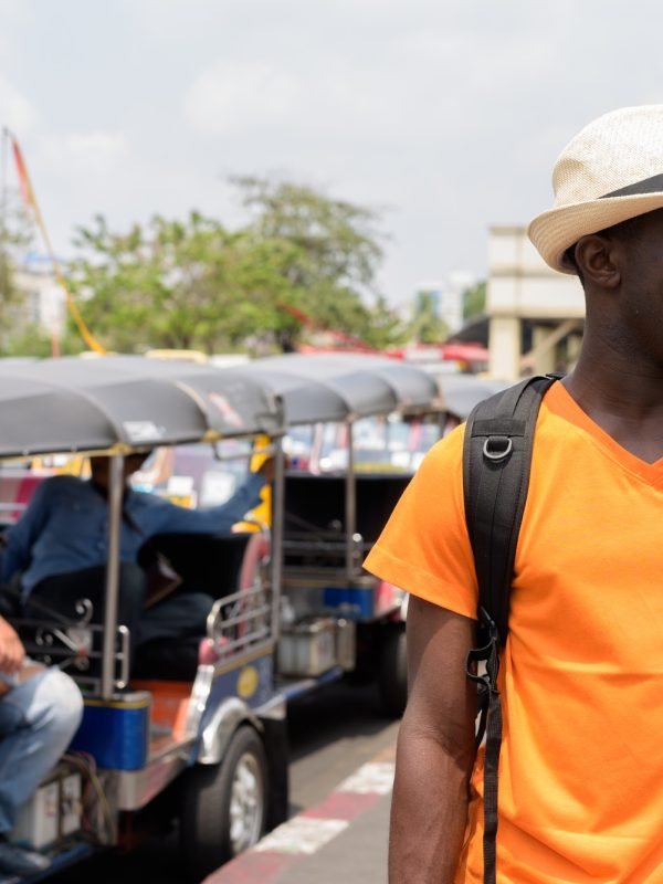 Happy black African tourist man in Bangkok with tuk tuk taxis