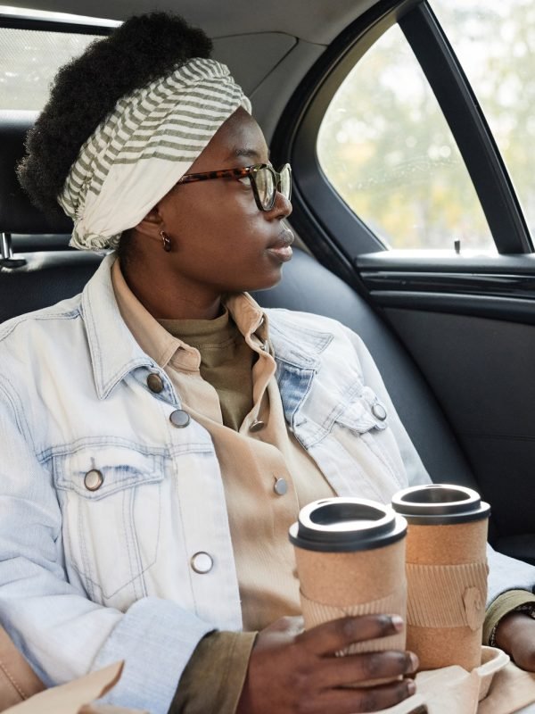 Woman with coffee sitting in taxi