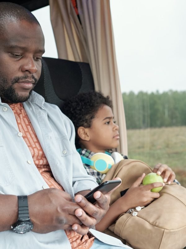 Young African male passenger scrolling in smartphone